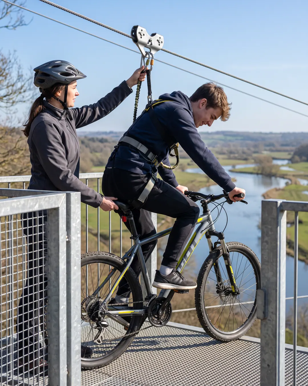 Operator clipping a rider into the safety system before a high cable ride